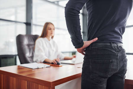 Rear view. Woman and man in formal clothes working together indoors in the office by table.の写真素材