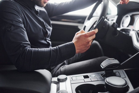 Man in elegant clothes sitting in brand new expencive automobile.