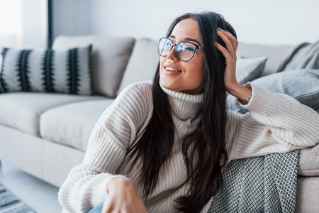 Young beautiful woman in glasses sitting at home alone.