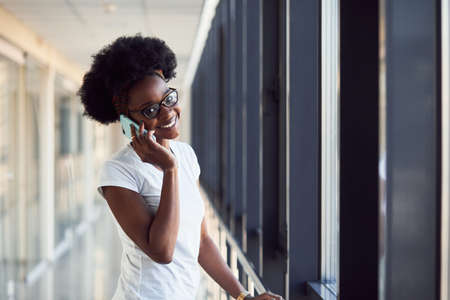Young african american female passanger in casual clothes is in airport with phone.の写真素材