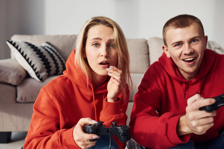 Young lovely couple together at home playing video games at weekend and holidays time together.