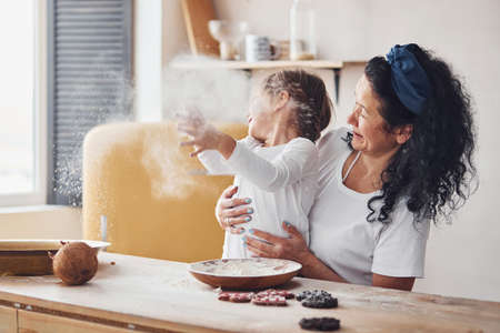Senior woman with her granddaughter preparing food with flour on kitchen and have fun.の写真素材