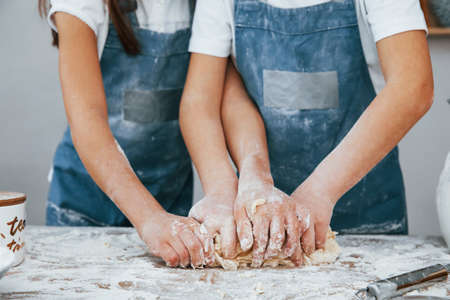 Close up view of two little girls in blue chef uniform that preparing food on the kitchen.の写真素材