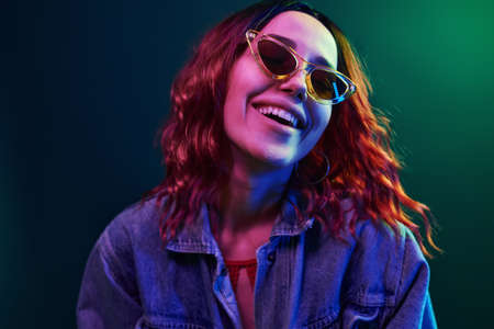 Portrait of young girl in glasses in red and blue neon in studio.の写真素材