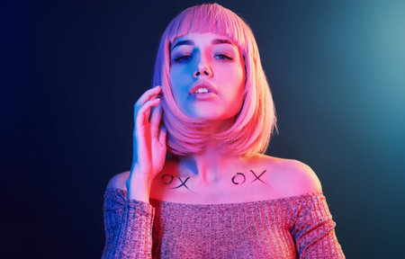 Portrait of young girl with blond hair in red and blue neon in studio.