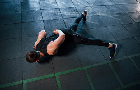 Strong young man in sportive clothes doing push ups in gym.