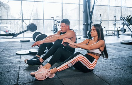 Young sportive people doing abs together in the gym.