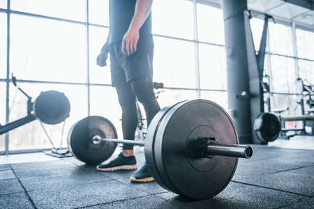 Strong young man in sportive clothes doing exercises with heavy weights in the gym.の写真素材