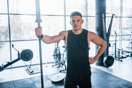Strong young man in sportive clothes standing in the gym.