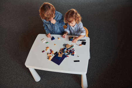 Little friends have fun with construction toys in playroom. Kindergarten educational games.の写真素材