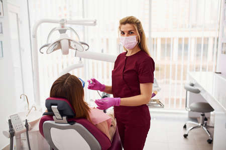 Little girl in protective glasses visiting dentist in clinic. Conception of stomatology.の写真素材
