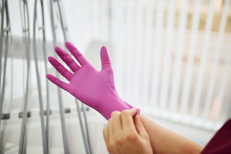 Close up view of female dentist in uniform wearing gloves in stomatology office.