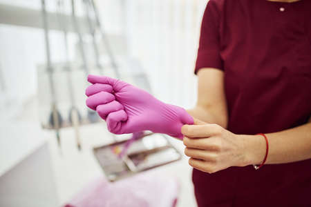 Close up view of female dentist in uniform wearing gloves in stomatology office.の写真素材