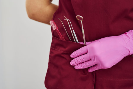 Close up view of female dentist in uniform that standing in stomatology office with tools in pocket.