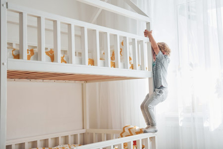 Cute little boy resting and have fun indoors in room on the bed.