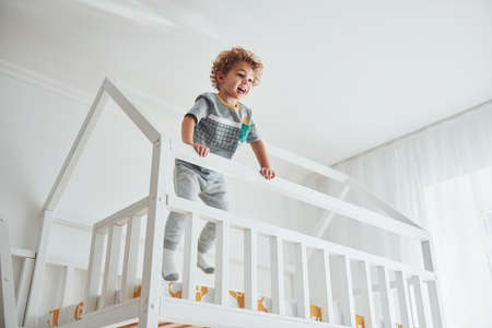 Cute little boy resting and have fun indoors in room on the bed.の写真素材