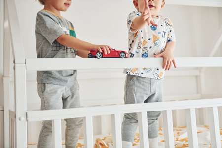 Two little boys resting and have fun indoors in the bedroom together.の写真素材