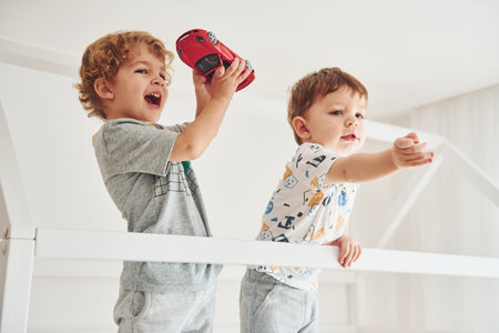 Two little boys resting and have fun indoors in the bedroom together.