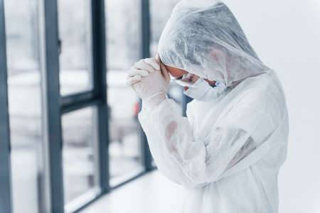 Feeling bad, tired and depressed. Portrait of female doctor scientist in lab coat, defensive eyewear and mask.の写真素材