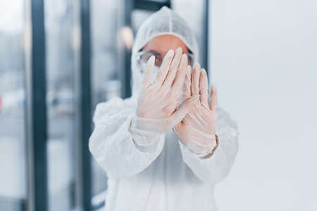 Stop the virus sign. Portrait of female doctor scientist in lab coat, defensive eyewear and mask.の写真素材
