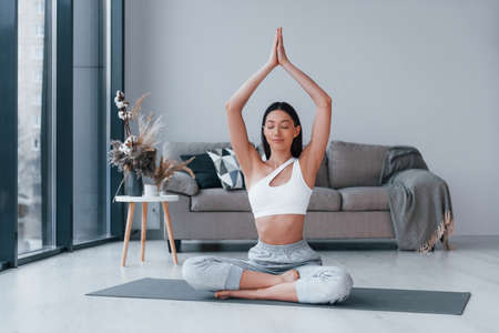 Does yoga exercises. Young woman with slim body shape in sportswear have fitness day indoors at home.の写真素材