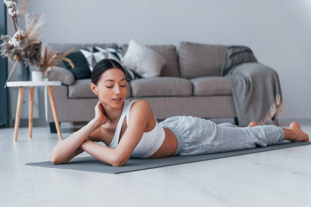 Lying down on the mat and taking a break. Young woman with slim body shape in sportswear have...