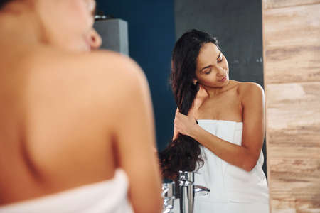 Beautiful young woman standing in bathroom near the mirror.の写真素材