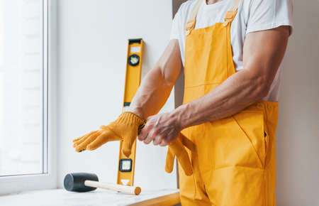 Handyman in yellow uniform preparing for work indoors. House renovation concept.の写真素材