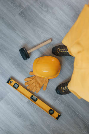 Tools on the floor. Handyman in yellow uniform standing indoors. House renovation conception.の写真素材