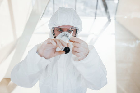 Holds syringe with medicine. Female doctor scientist in lab coat, defensive eyewear and mask...