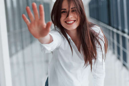 Brunette in white shirt indoors in modern airport or hallway at daytime.の写真素材