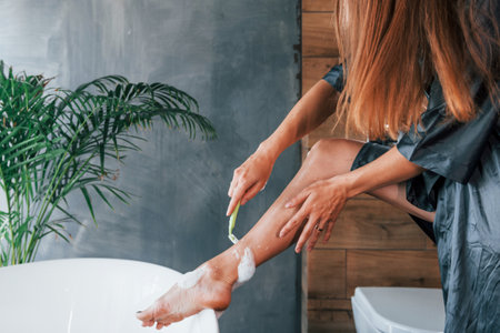 Beautiful young woman have free time at home in the bath. Shaves legsの写真素材