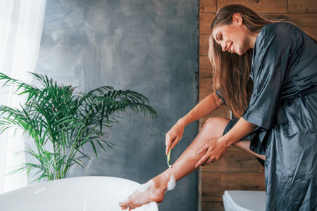 Beautiful young woman have free time at home in the bath. Shaves legsの写真素材