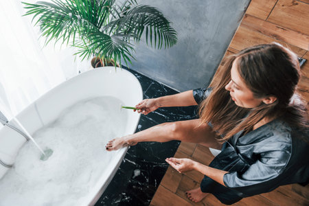 Beautiful young woman have free time at home in the bath. Shaves legsの写真素材