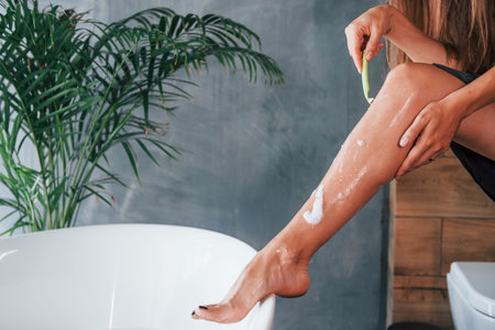 Beautiful young woman have free time at home in the bath. Shaves legsの写真素材