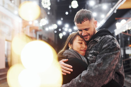 Embracing each other. Happy multiracial couple together outdoors in the city celebrating New yearの写真素材