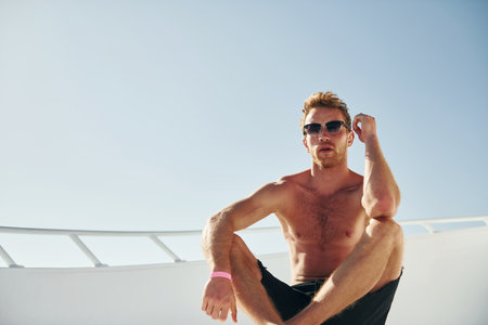 Warm weather. Young male tourist is on the yacht on the sea. Conception of vacationの写真素材