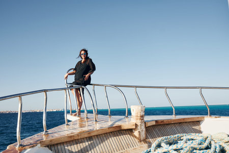 Mature woman standing on the yacht and enjoying her vacation on the sea