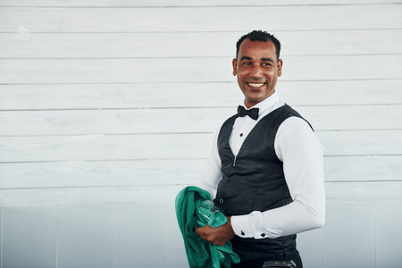 Black waiter in formal clothes is at his work outdoors at sunny daytimeの写真素材