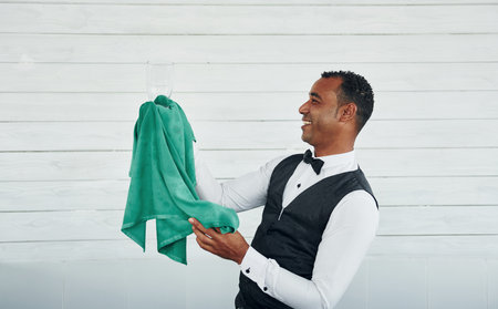 Black waiter in formal clothes is at his work outdoors at sunny daytimeの写真素材