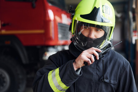 Male firefighter in protective uniform standing near truckの写真素材