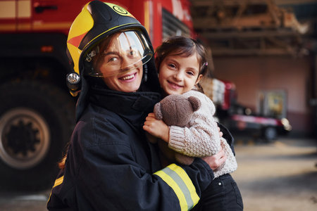 Happy little girl is with female firefighter in protective uniformの写真素材