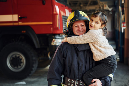 Happy little girl is with male firefighter in protective uniformの写真素材