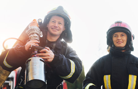 Male and female firefighters in protective uniform is outdoors togetherの写真素材