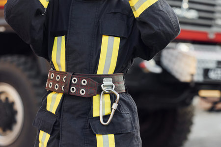Female firefighter in protective uniform standing near truck