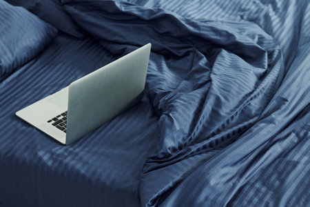 Laptop is on the bed. Interior and design of beautiful modern bedroom at daytimeの写真素材