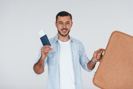Tourist with ticket. Young handsome man standing indoors against white backgroundの写真素材