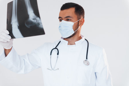 Medic with x-ray. Young handsome man standing indoors against white backgroundの写真素材
