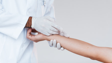 Medic works with patients hand. Close up particle view of young man that standing indoors against white backgroundの写真素材