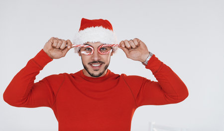 With candies. Young handsome man in New year clothes standing indoors against white backgroundの写真素材